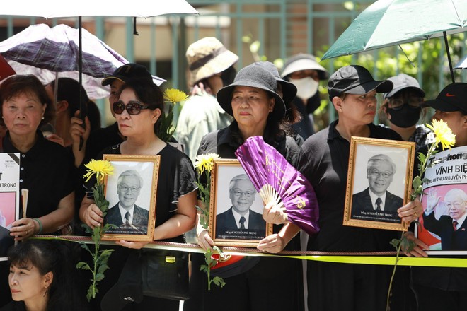 Nhiều người mang ảnh Tổng Bí thư Nguyễn Phú Trọng và hoa cúc, bày tỏ lòng thành kính