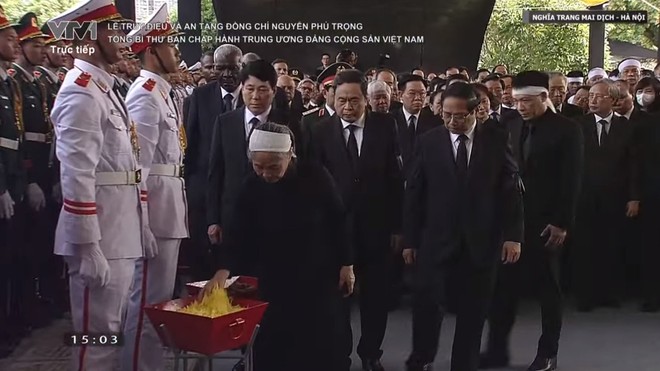 Bà Ngô Thị Mận, phu nhân của Tổng Bí thư Nguyễn Phú Trọng rải những cánh hoa xuống huyệt mộ của Tổng Bí thư.