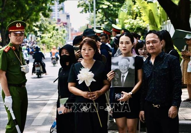 Nhiều người mang ảnh Tổng Bí thư Nguyễn Phú Trọng và hoa trắng, bày tỏ lòng thành kính