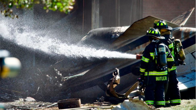 Lính cứu hỏa phun nước tại hiện trường vụ tai nạn máy bay (Ảnh: AP)