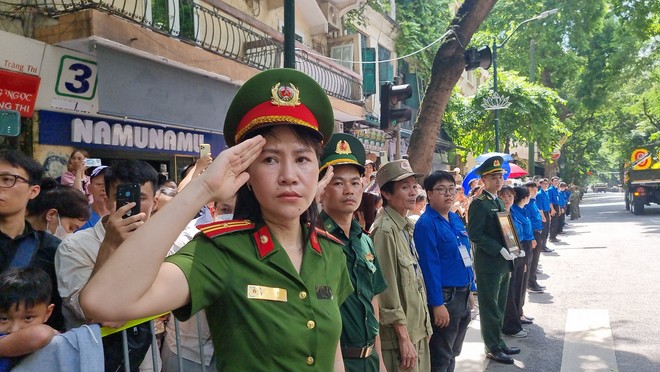 Các lực lượng công an, quân đội, dân phòng, thanh niên tình nguyện cùng đông đảo nhân dân xúc động chào khi đoàn xe tang Tổng Bí thư Nguyễn Phú Trọng đi qua. Ảnh: Minh Quân