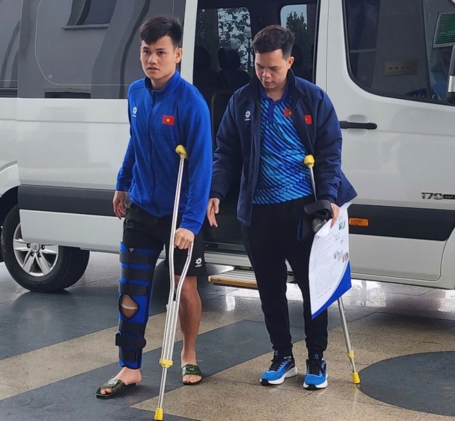 Tấn Tài (trái) bị bó chân và phải di chuyển cùng đôi nạng Tấn Tài (trái) bị bó chân và phải di chuyển cùng đôi nạng