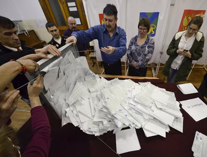 Các thành viên trong tổ bầu cử địa phương đổ hòm phiếu ra để kiểm