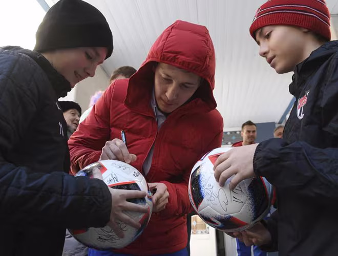 Tuyển thủ bóng đá quốc gia Nga Daler Kuzyayev ký tặng lên trái bóng khi ghé thăm một điểm bỏ phiếu