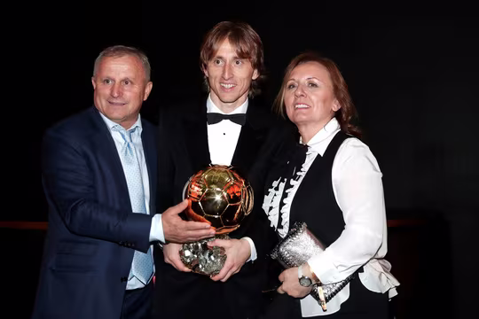 Modric nở nụ cười hạnh phúc chụp ảnh cùng với cha mẹ. Modric nở nụ cười hạnh phúc chụp ảnh cùng với cha mẹ.