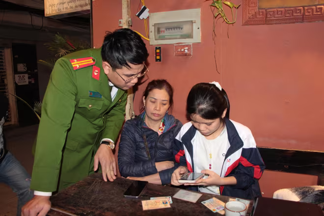 Trung tá Trần Xuân Bình và sinh viên tình nguyện hướng dẫn người dân cập nhật thông tin dữ liệu đăng ký xe, giấy phép lái xe tại quán cà phê