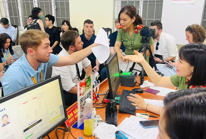 Cán bộ chiến sĩ Công an phường Hà Đông hướng dẫn người nước ngoài thực hiện thủ tục cấp tài khoản định danh điện tử VNeID