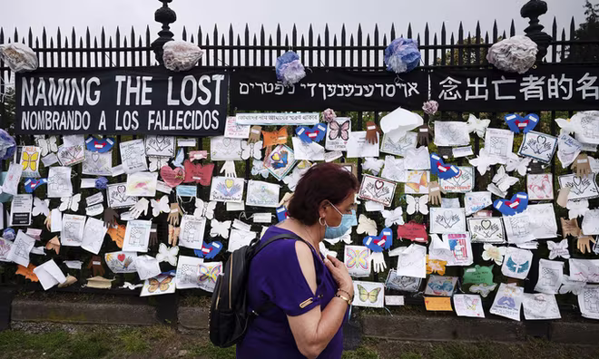 Một phụ nữ đi qua bức tường nghĩa trang tưởng niệm những người thiệt mạng vì đại dịch Covid-19 thành phố New York của Mỹ