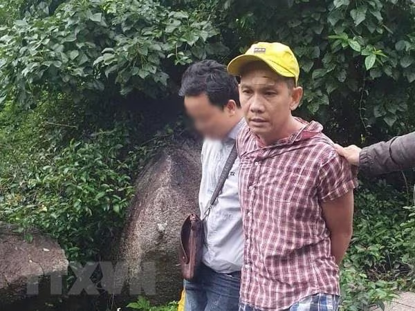 Nghi phạm Lê Trường Thành (áo kẻ) bị bắt giữ. Ảnh: TTXVN Nghi phạm Lê Trường Thành (áo kẻ) bị bắt giữ. Ảnh: TTXVN