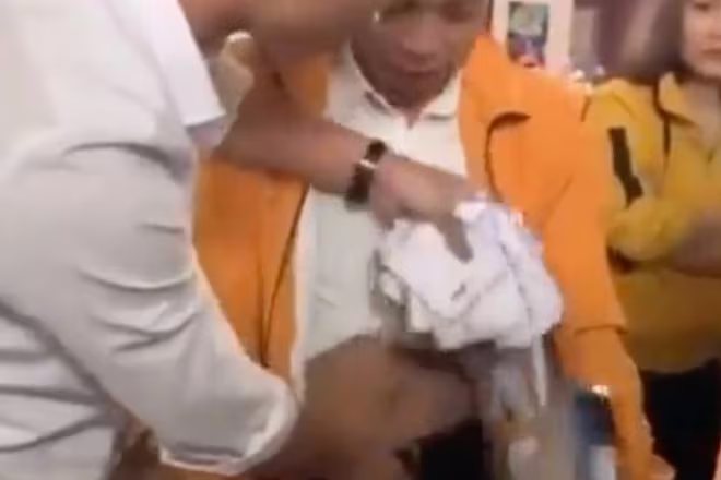 Người nhà bà Huệ lôi số phong bì bị giấu trong quần Giang. Ảnh: Cắt từ clip Người nhà bà Huệ lôi số phong bì bị giấu trong quần Giang. Ảnh: Cắt từ clip