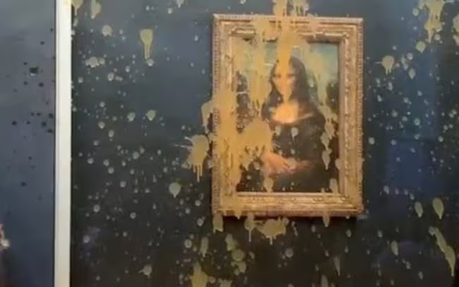 Hai người biểu tình đã hắt nước súp màu cam lên tấm kính bảo vệ bức tranh Mona Lisa Hai người biểu tình đã hắt nước súp màu cam lên tấm kính bảo vệ bức tranh Mona Lisa