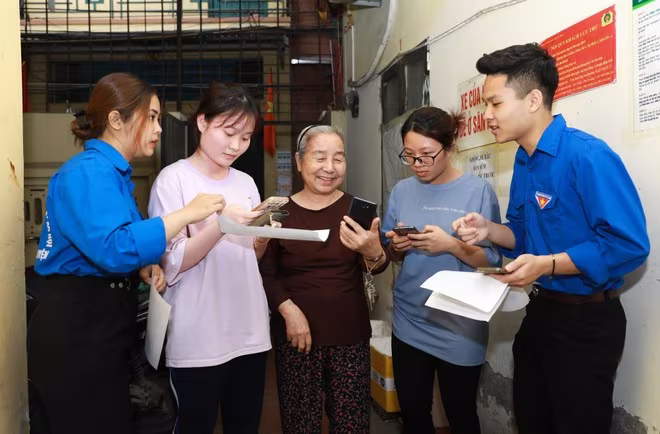 Những sinh viên tình nguyện của trường Đại học Lao động xã hội đồng hành cùng Công an phường Trung Hòa đến từng hộ dân hướng dẫn cài đặt VNeID